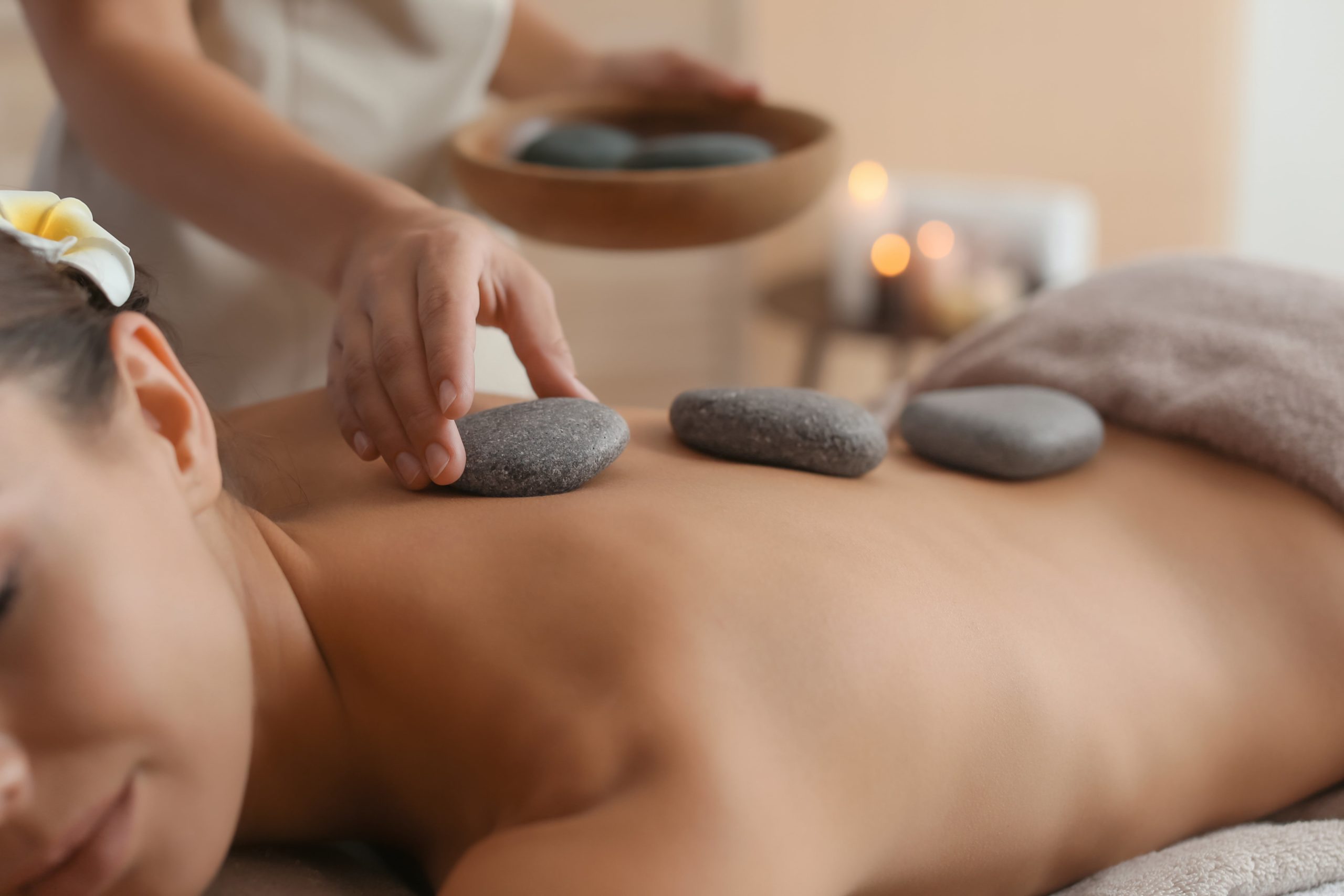 A Woman Getting Hot Stone Massage | Know more at Spa Vela in Flower Mound, Texas