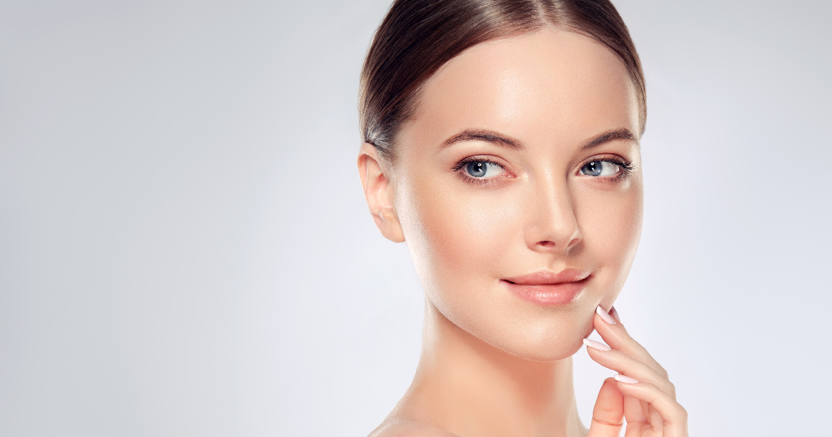 Woman with flawless, glowing skin gently touching her face, showcasing the radiant results of a HydraFacial in Flower Mound, TX.